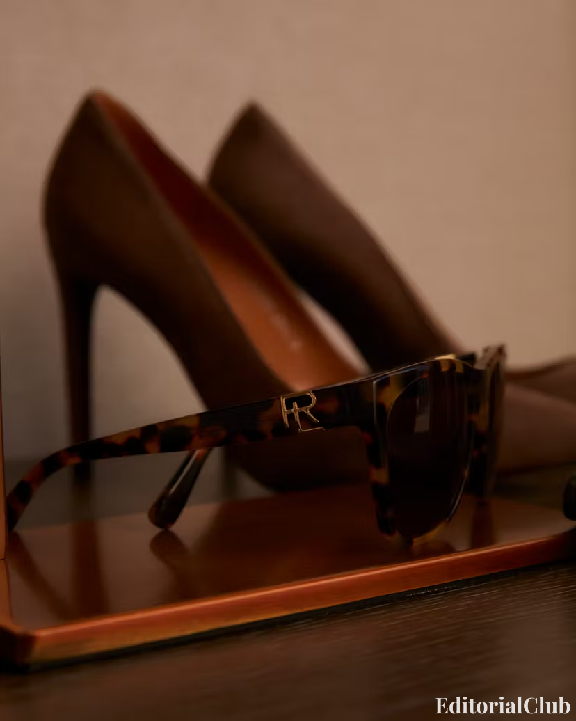 Tortoiseshell Ralph Lauren sunglasses displayed next to brown high heels on a wooden tray – fashion still life.