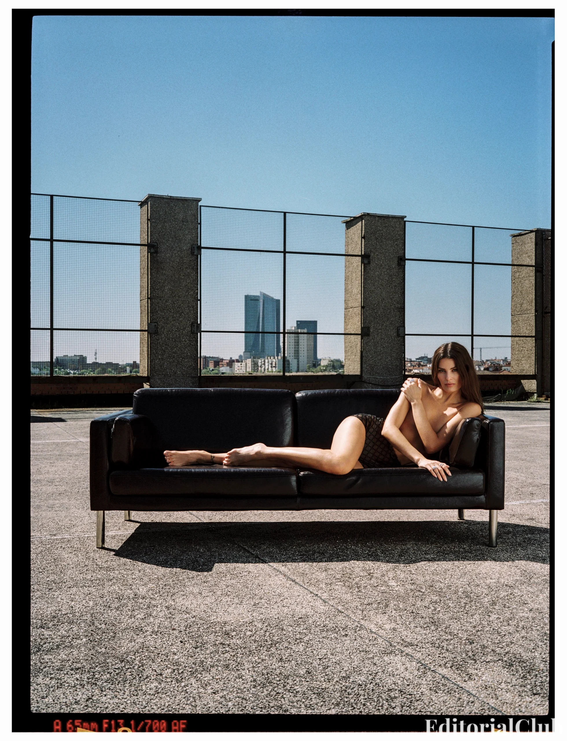 Isabeli Fontana posing nude on a rooftop leather couch with skyscrapers in the background for Numéro Netherlands May 2025 cover editorial.
