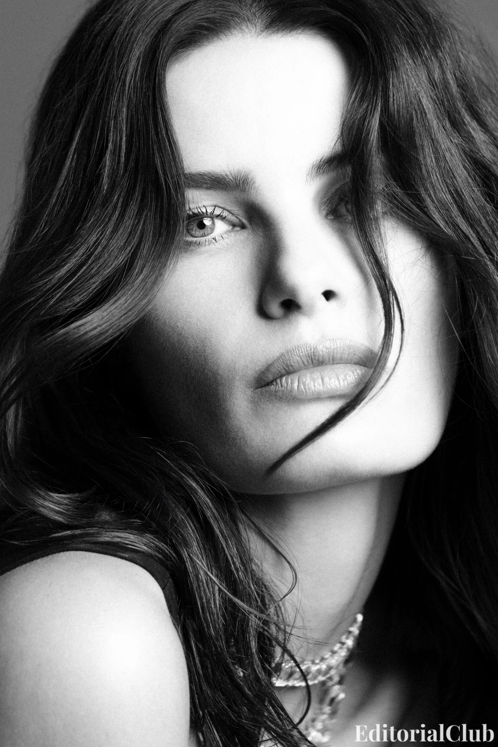 Black and white close-up portrait of Isabeli Fontana with loose waves and a soft gaze, highlighting her natural beauty.
