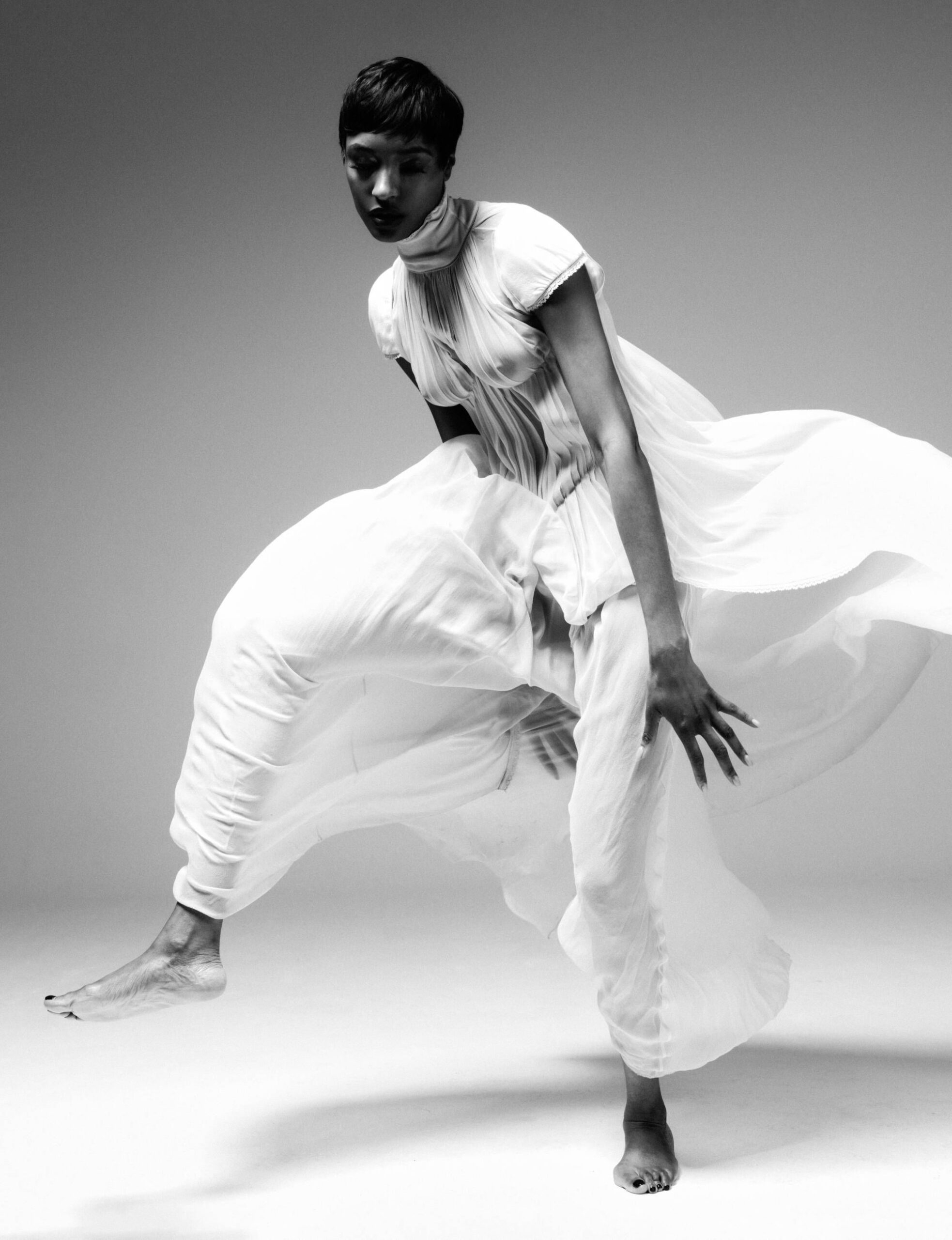 Jourdan Dunn in motion wearing a flowing white gown in a black-and-white fashion portrait