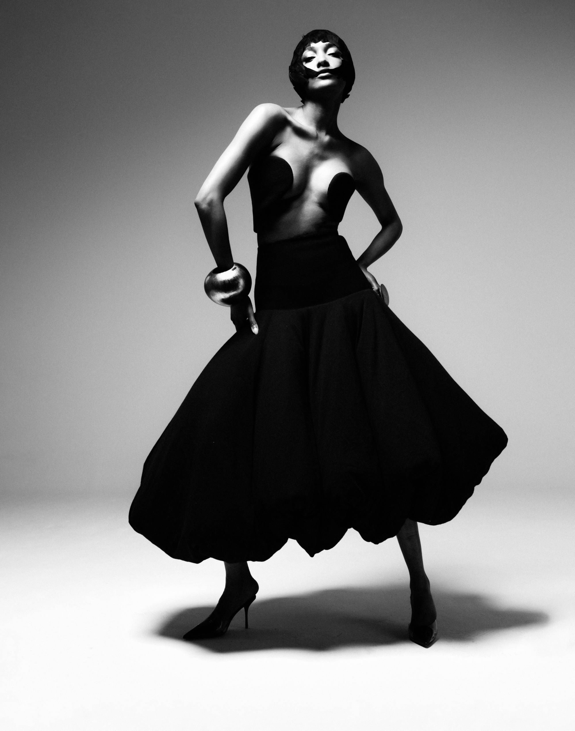 Jourdan Dunn in a dramatic black ballgown and sculptural accessories in a monochrome studio shot