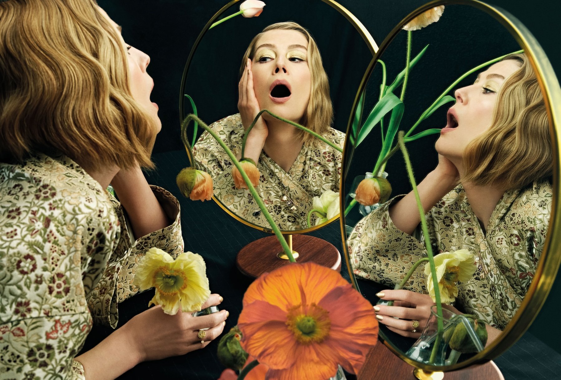 Rosamund Pike gazing into mirrors with dramatic expression and floral arrangement for Harper’s Bazaar UK editorial