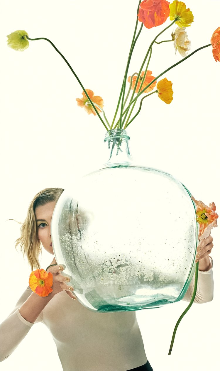 Rosamund Pike holding a giant glass vase filled with colorful poppies in a minimalist floral concept shoot
