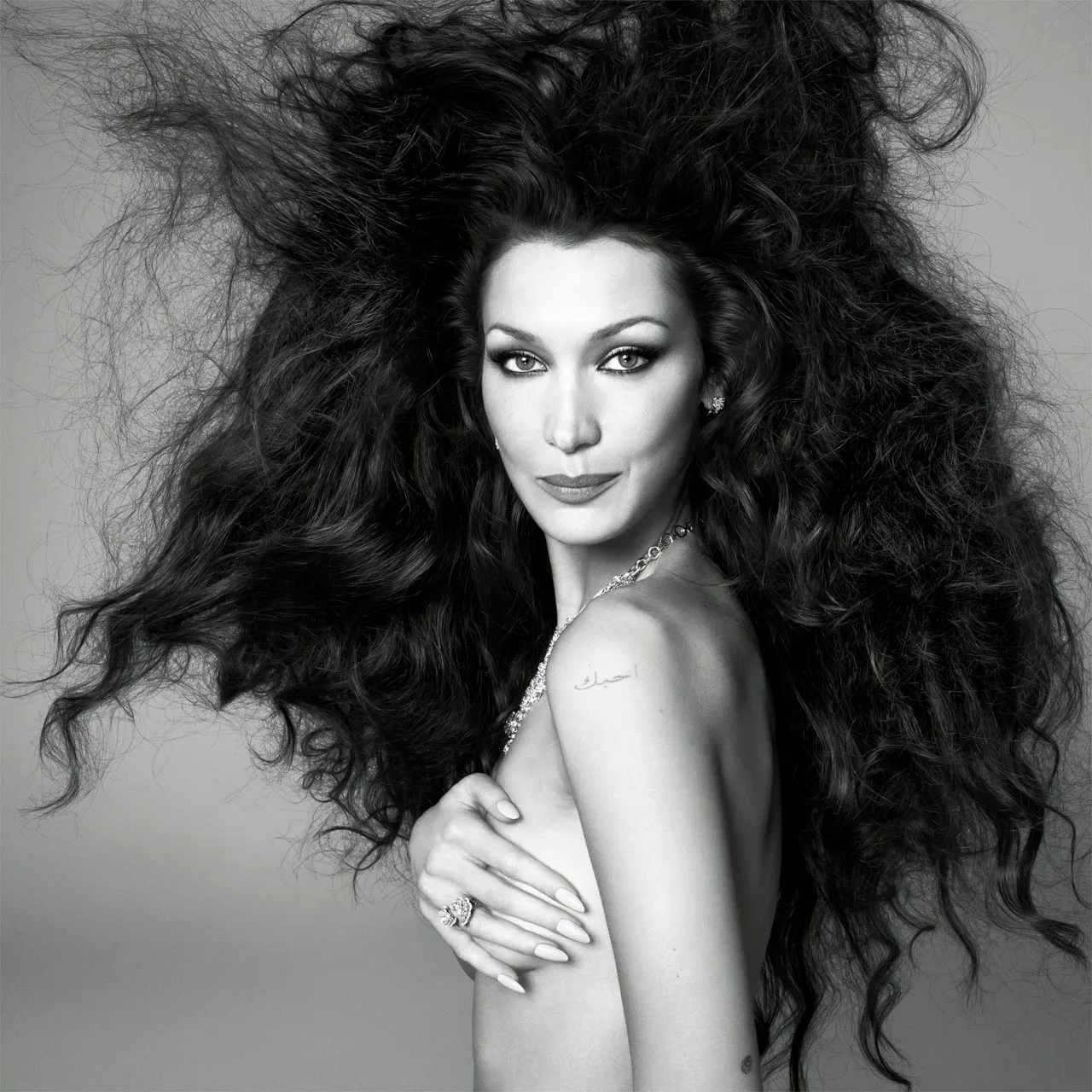Bella Hadid topless with signature big hair and confident gaze, showcasing body positivity and natural beauty for British Vogue June 2025.