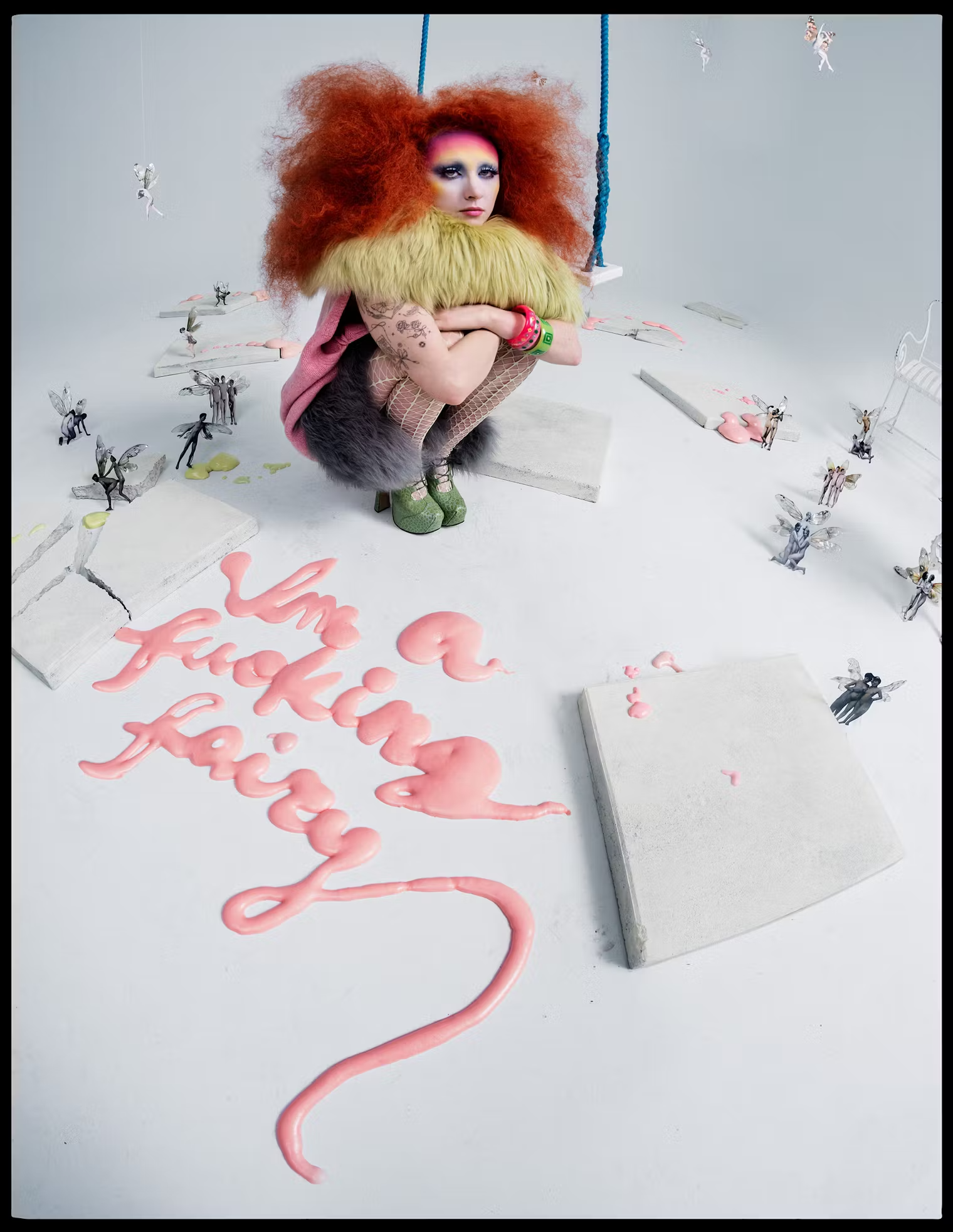 Squatting in the middle of a whimsical white set, Chappell Roan poses with big red hair and pink lettering spelling 'I'm a f***ing fairy' on the floor – W Magazine, May 2025.