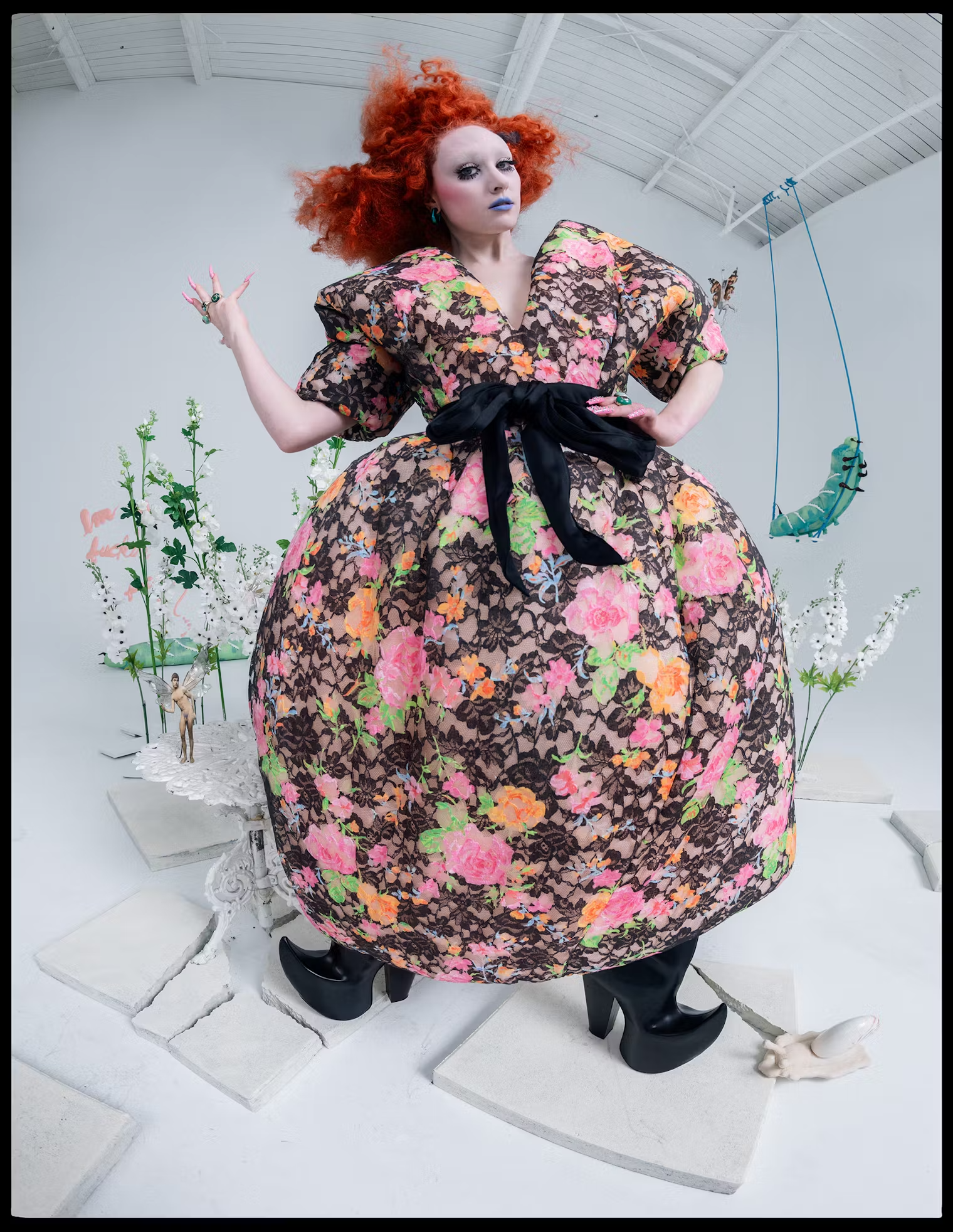 Chappell Roan wears a voluminous floral gown with black lace and platform heels, framed by whimsical props and fairy figurines – W Magazine Pop Issue, May 2025 fashion editorial.