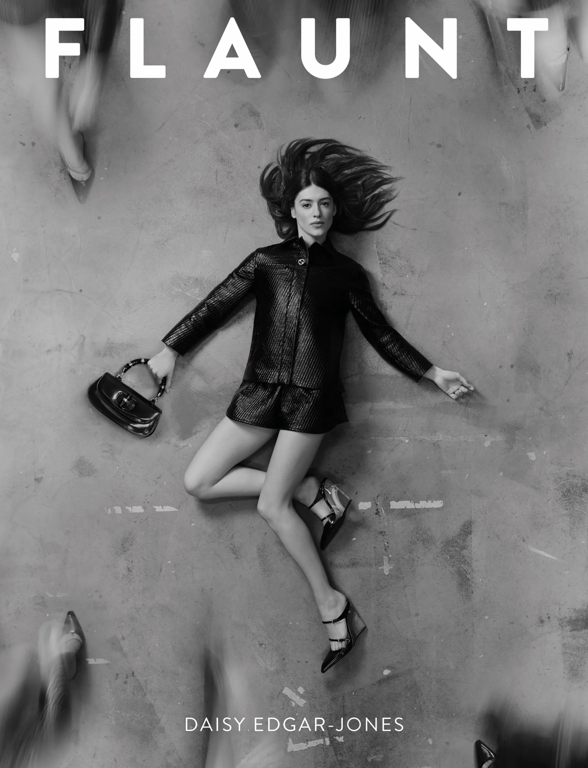 Daisy Edgar-Jones lies on a concrete floor in a black textured set and heels, featured on the cover of Flaunt Magazine April 2025.