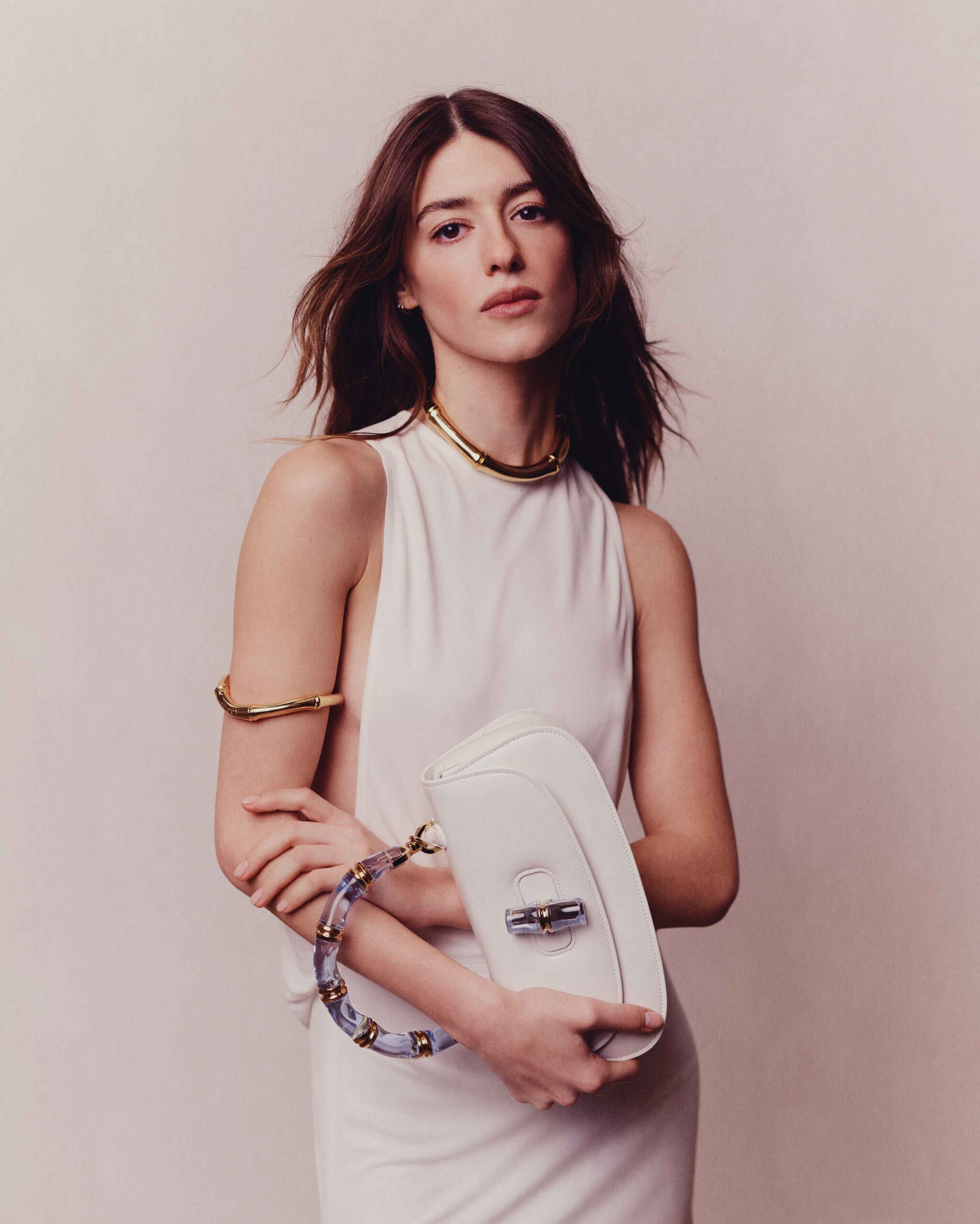 Elegant studio portrait of Daisy Edgar-Jones in a sleeveless white dress holding a designer handbag for Flaunt Magazine April 2025.