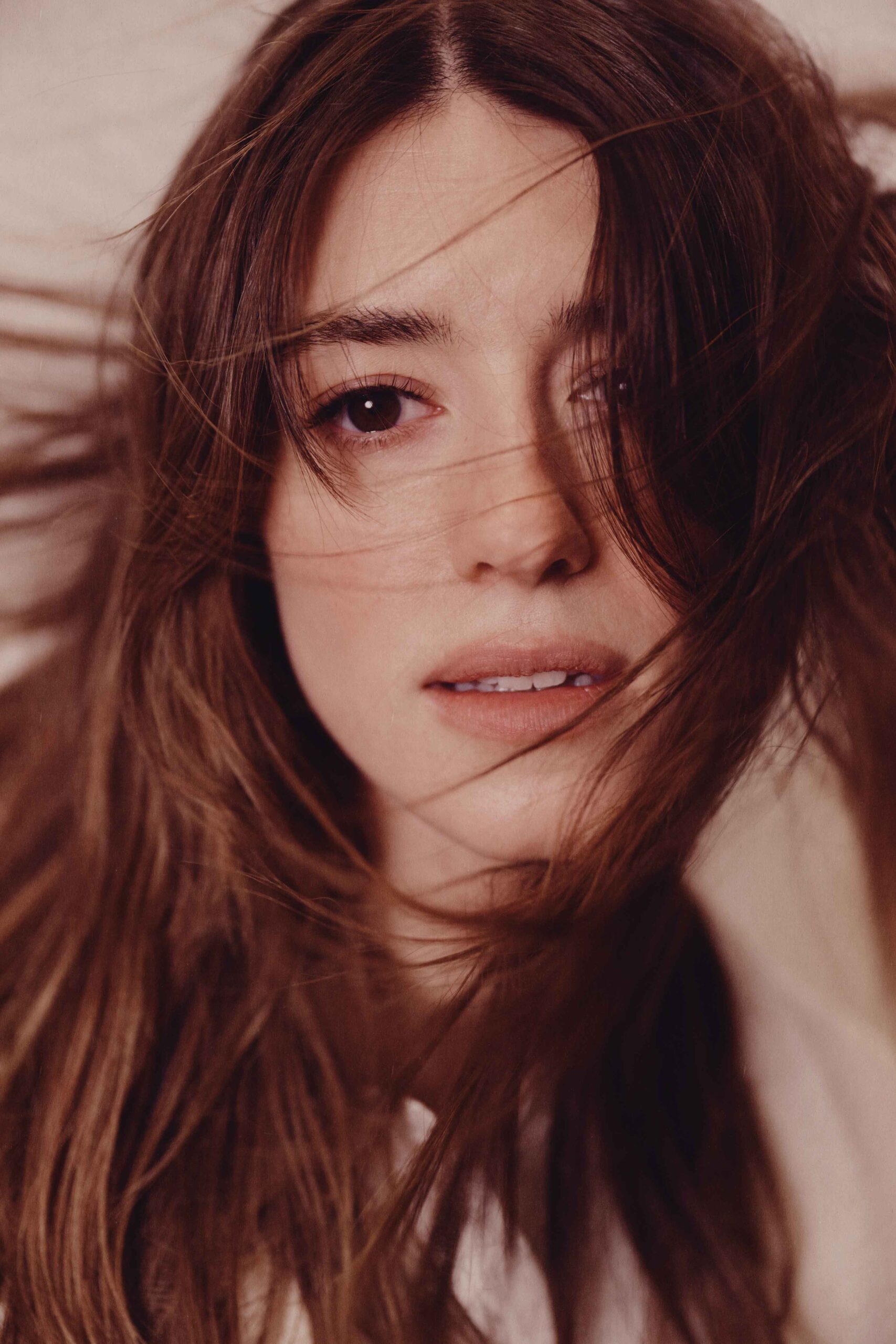 Close-up of Daisy Edgar-Jones with windswept hair and soft makeup, showcasing natural beauty and emotion.