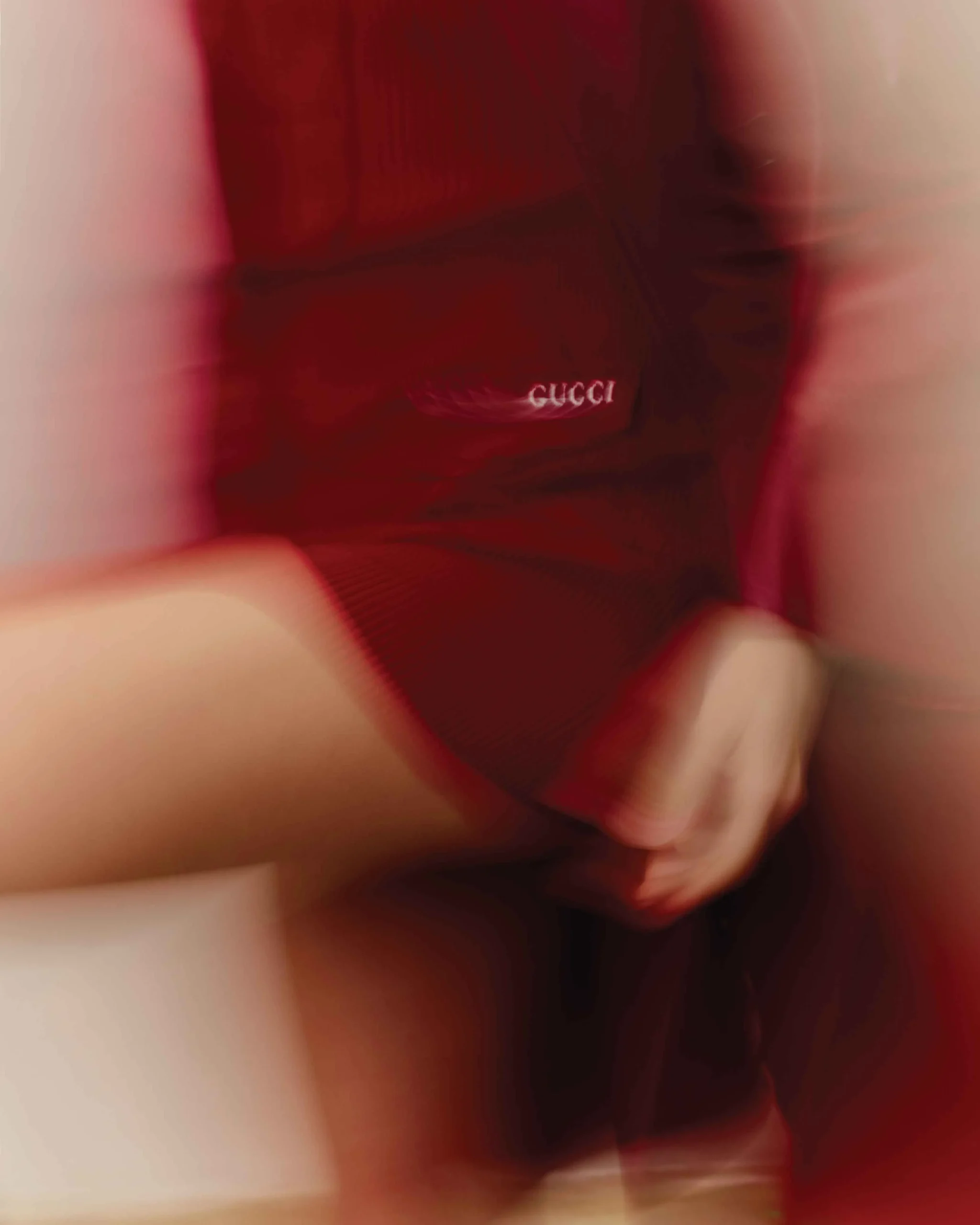 Motion-blurred close-up of a red Gucci outfit worn by Daisy Edgar-Jones, highlighting abstract fashion movement and brand detail.
