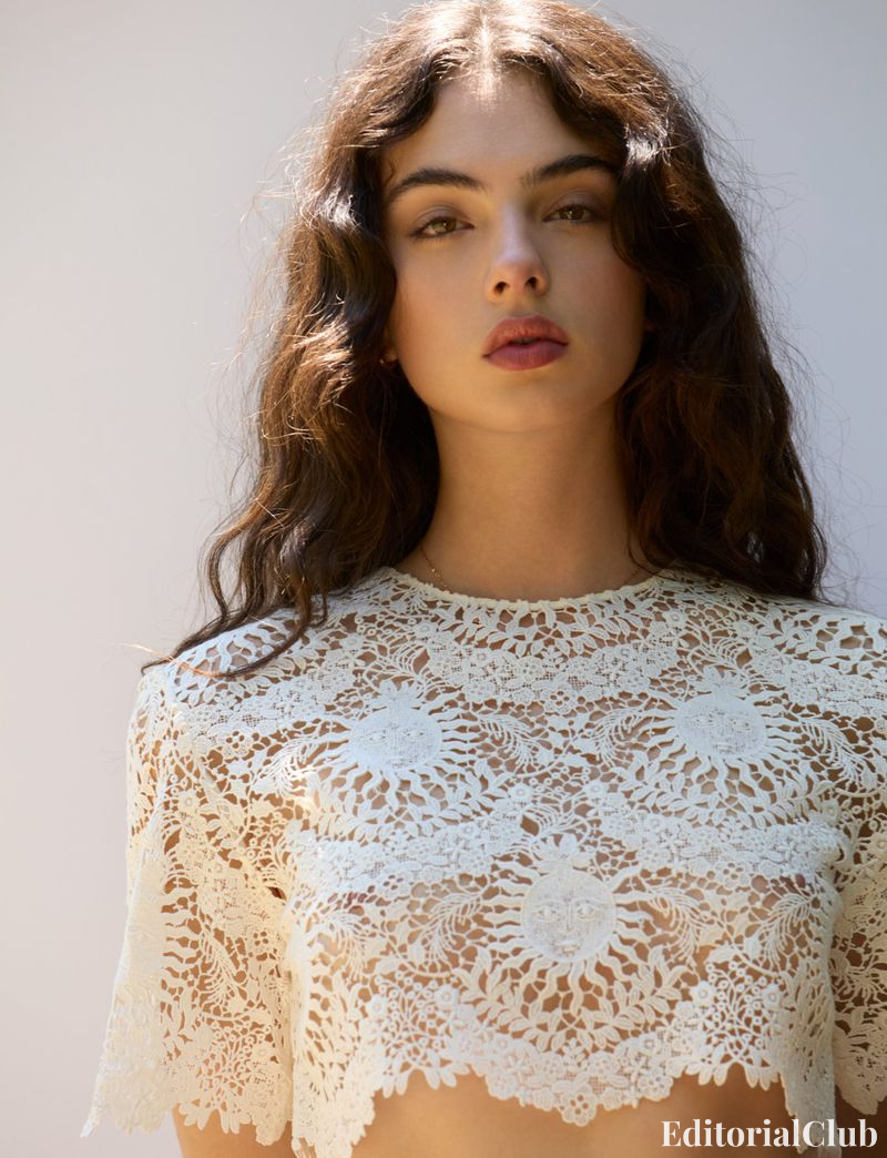 Deva Cassel in a cropped white lace top holding a flower, styled with natural waves – Elle France Summer 2024