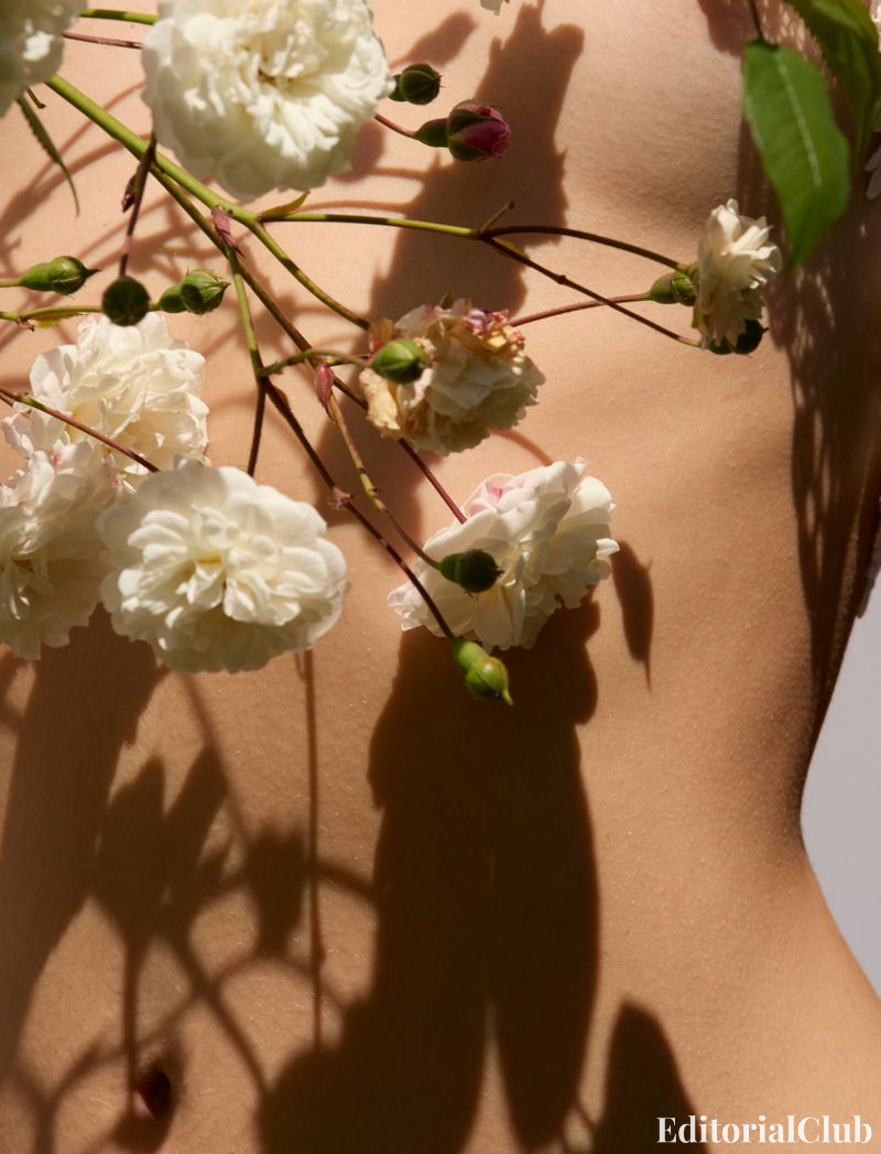 Close-up detail of flowers pressed against Deva Cassel’s skin, capturing the natural textures – Elle France artistic shot