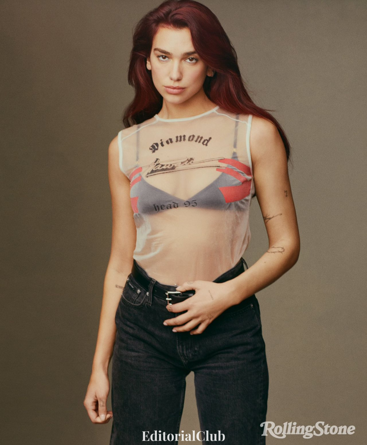 Dua Lipa arching back in sheer graphic top and jeans, showcasing tattoos in Rolling Stone editorial.