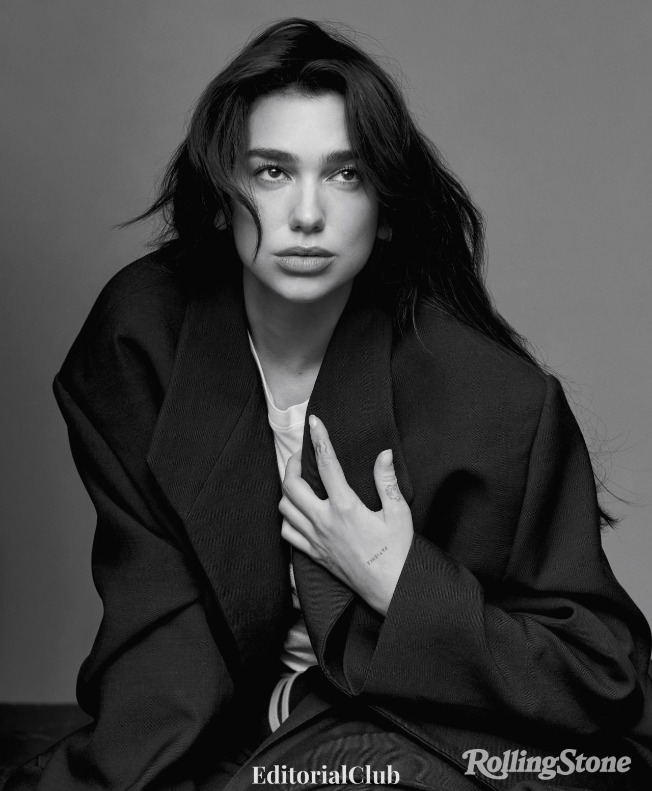 Black-and-white portrait of Dua Lipa gazing upward in a dramatic coat from her Rolling Stone editorial