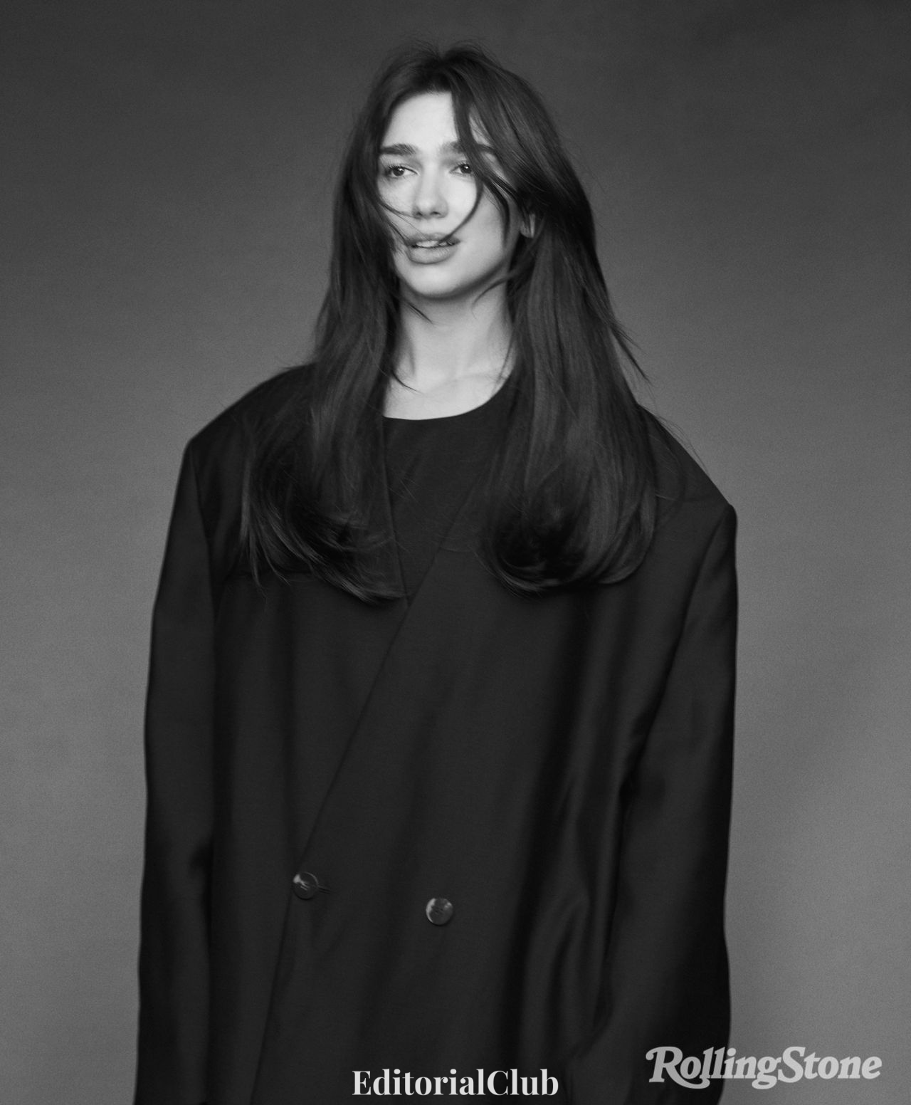 Dua Lipa smiling softly in a loose black blazer during her Rolling Stone 2024 feature shoot