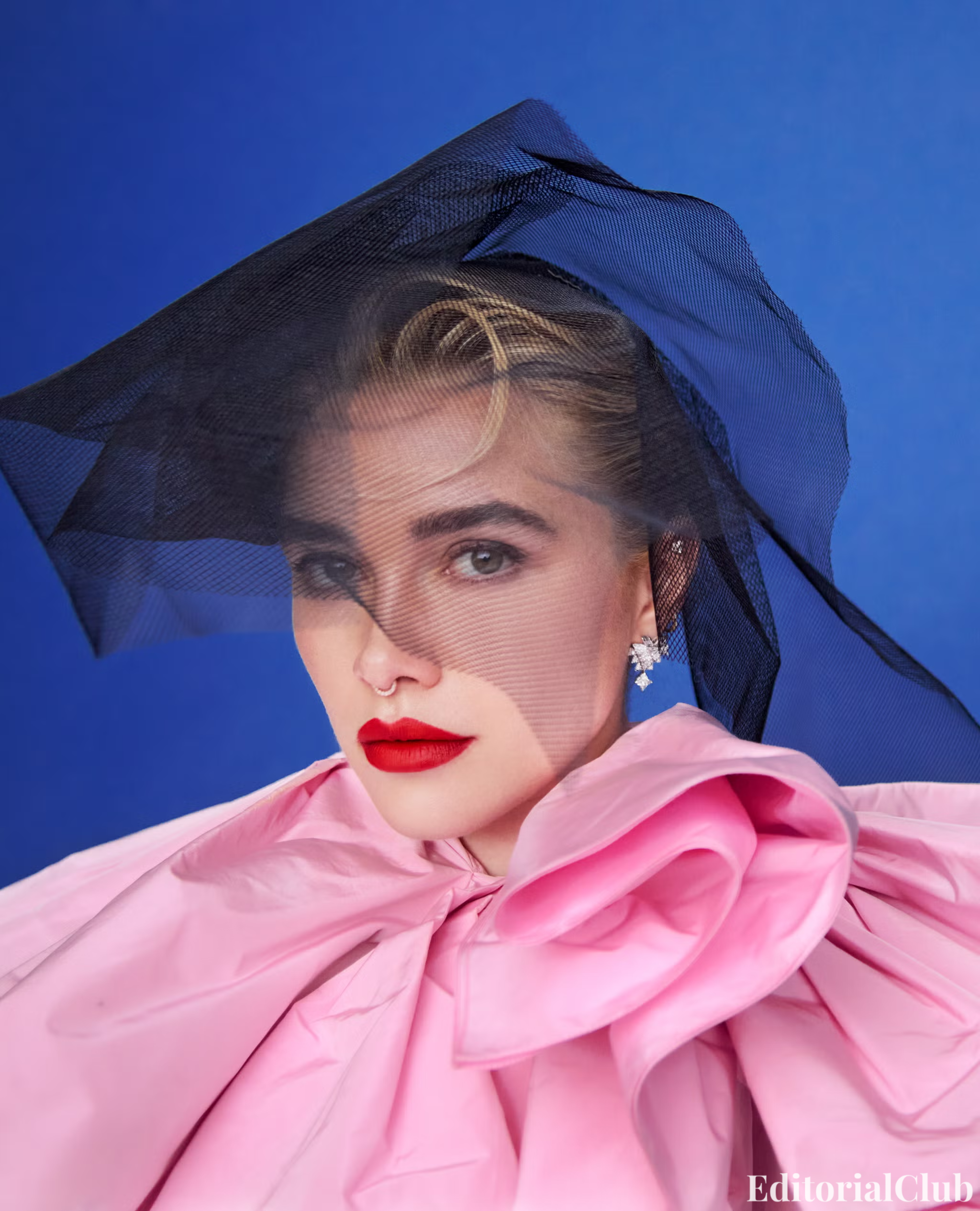 Close-up of Florence Pugh wearing a dramatic pink gown with a black mesh veil and bold red lipstick.