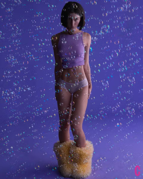Gracie Abrams stands in a lavender tank top, white mesh underwear, and fuzzy boots surrounded by bubbles for Cosmopolitan February 2025.