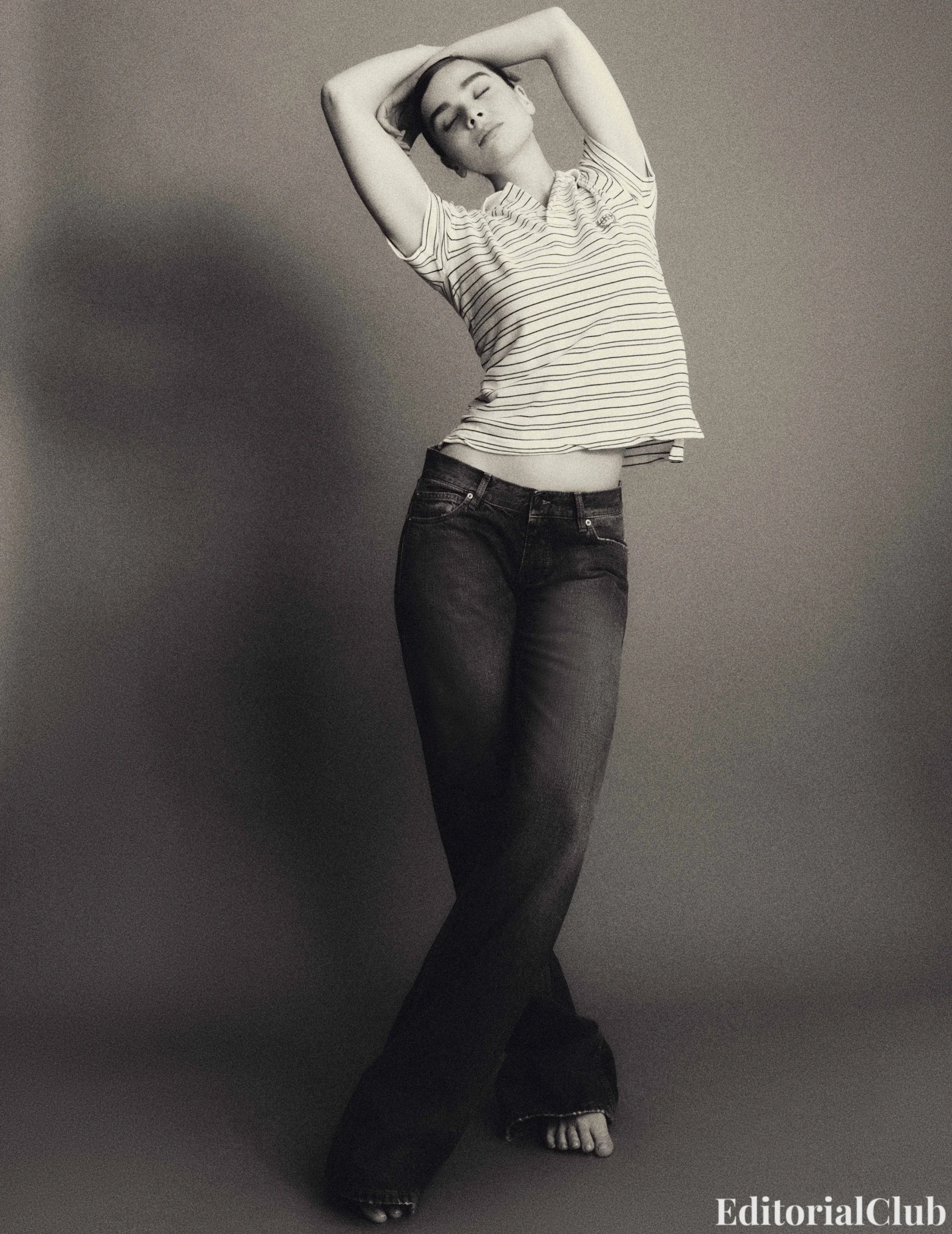 Hailee Steinfeld stretches gracefully in flared jeans and a striped tee in a monochrome portrait for Flaunt Magazine March 2025.