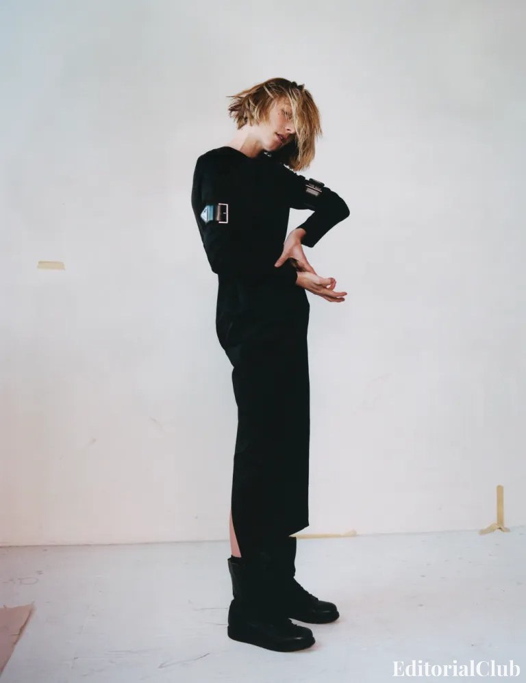 Hunter Schafer wearing a long black dress and boots, posing with tousled hair in a minimalist editorial portrait – i-D Magazine Spring 2022