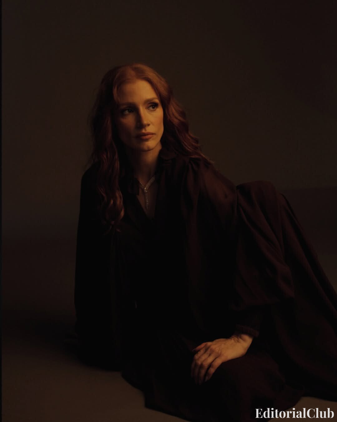 Jessica Chastain in a dark moody lighting setup wearing a flowing gown for ELLE Spain April 2025 artistic portrait