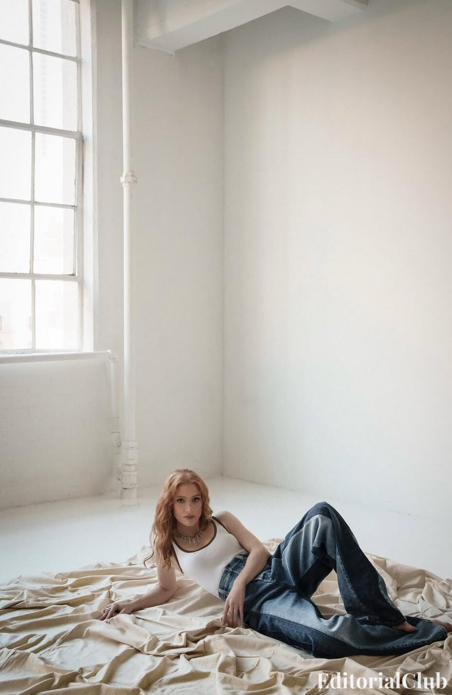 Jessica Chastain lounging on fabric in a white tank top and two-tone jeans – Elle Spain April 2025