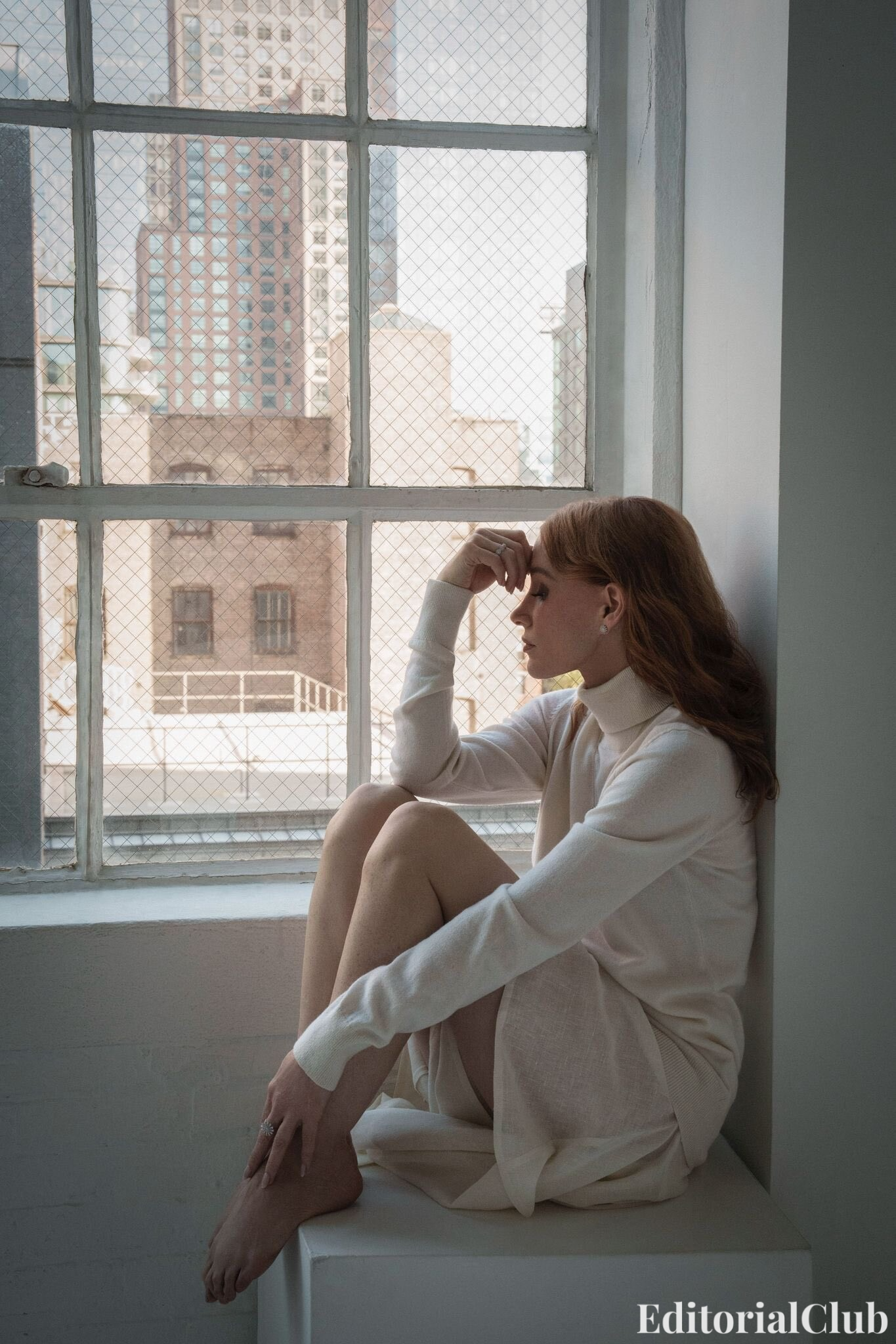 Jessica Chastain seated on windowsill in cream turtleneck dress – Elle Spain urban backdrop