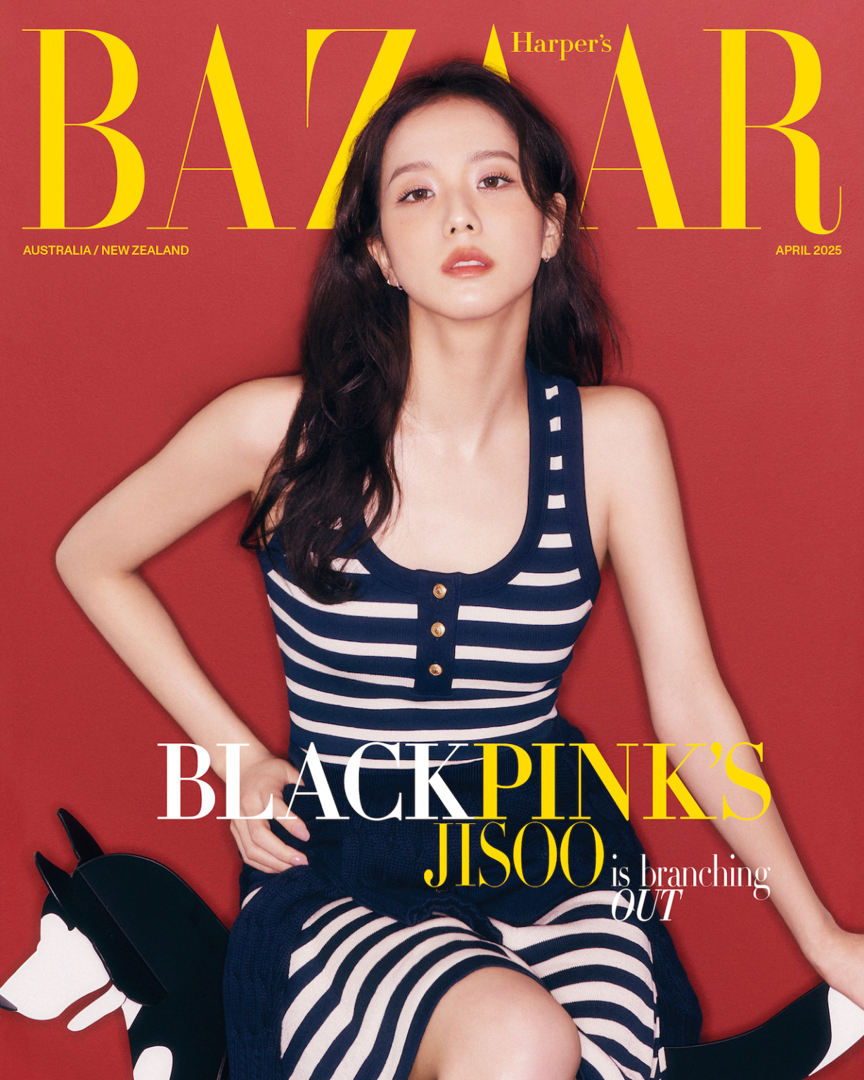 BLACKPINK’s Jisoo poses confidently on the April 2025 cover of Harper’s Bazaar Australia, wearing a navy and white striped sleeveless dress against a bold red backdrop.