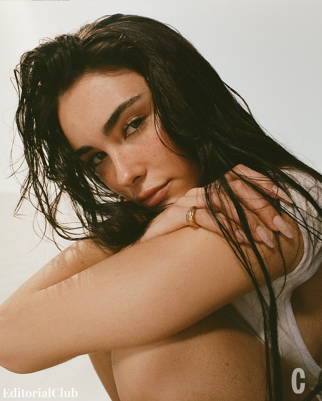 Close-up portrait of Madison Beer with wet hair and natural makeup, resting her head on her arms in a relaxed beachside setting for Cosmopolitan 2025.