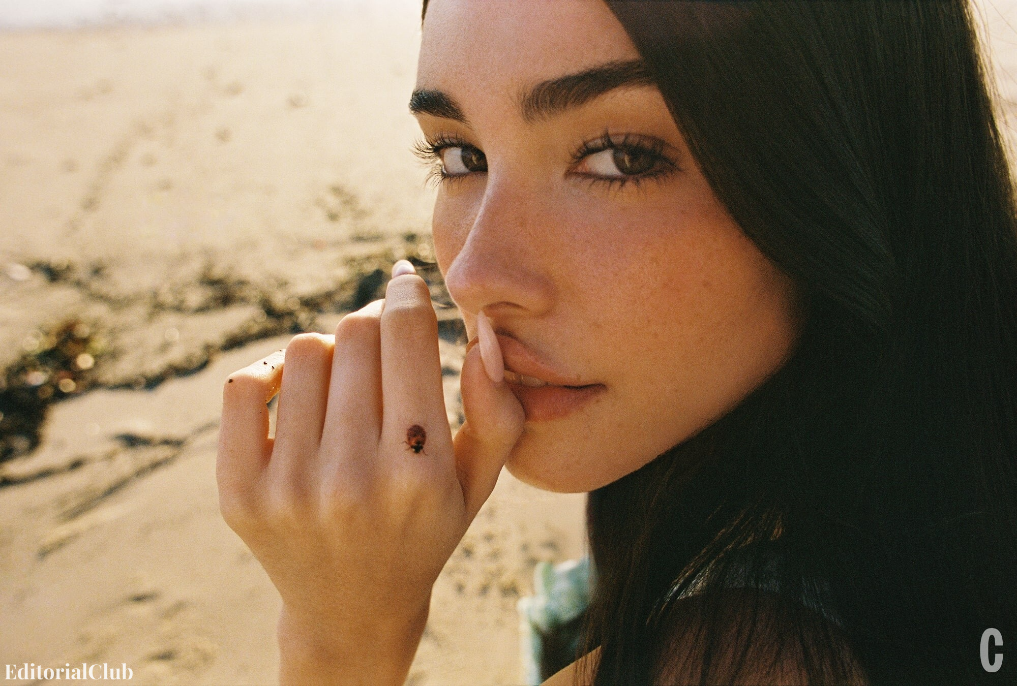Madison Beer on the beach, with a close-up of her face and a ladybug crawling on her finger.