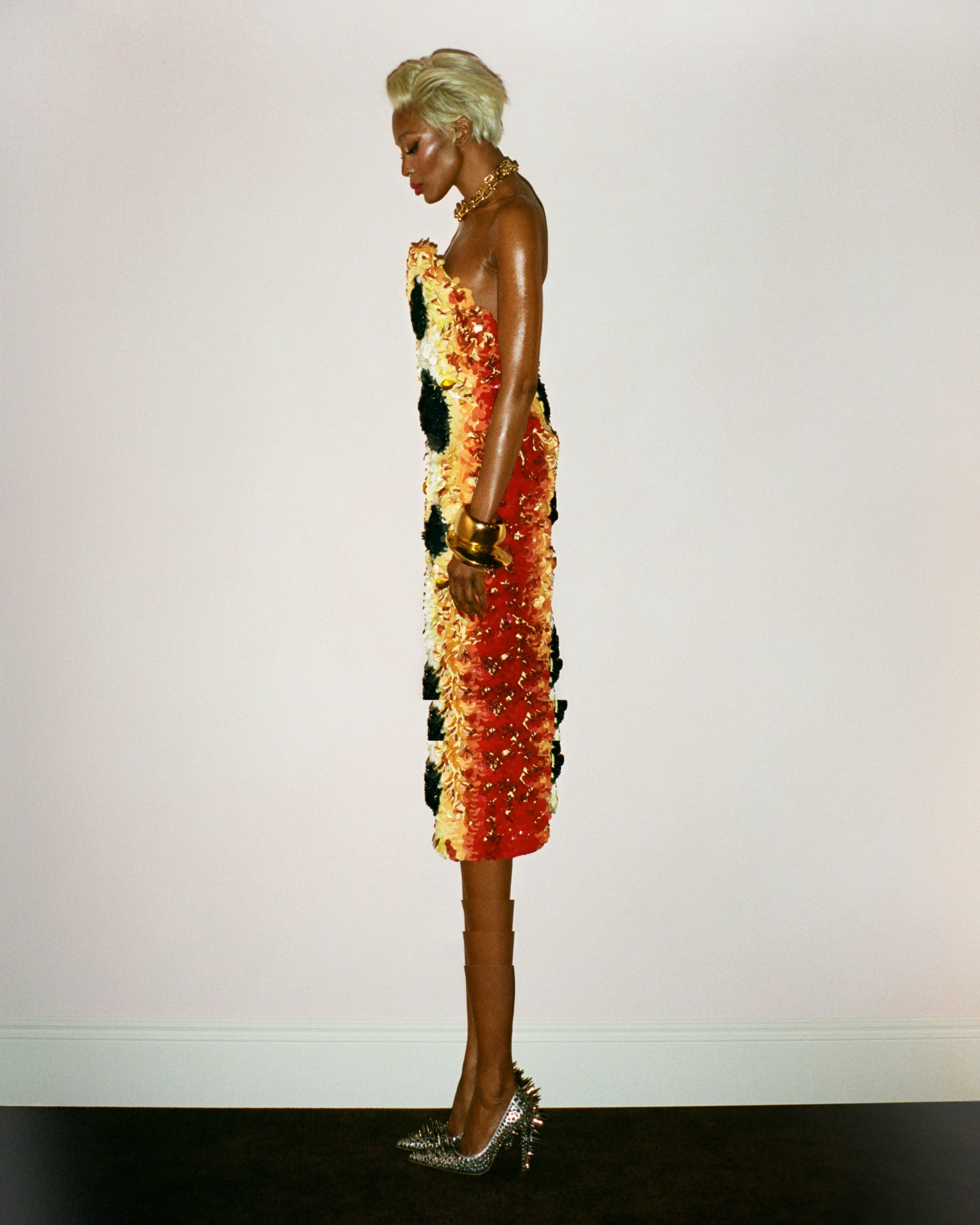Naomi Campbell poses in a strapless red and yellow textured dress with spiked heels for i-D Magazine March 2025 editorial.