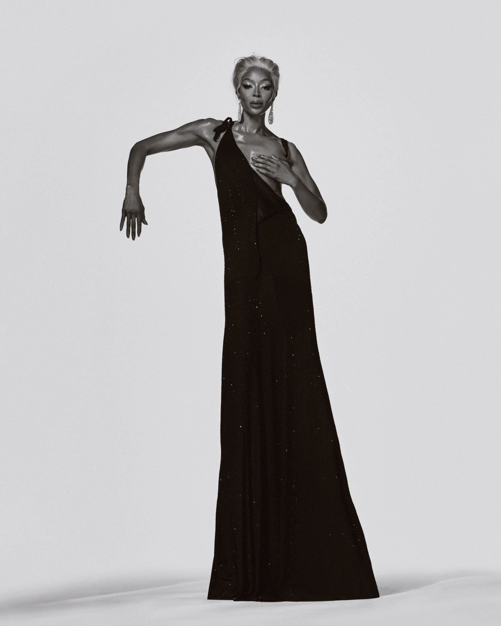 Naomi Campbell wears a black sparkling gown while striking an angular pose in a black-and-white editorial shot for i-D Magazine March 2025.