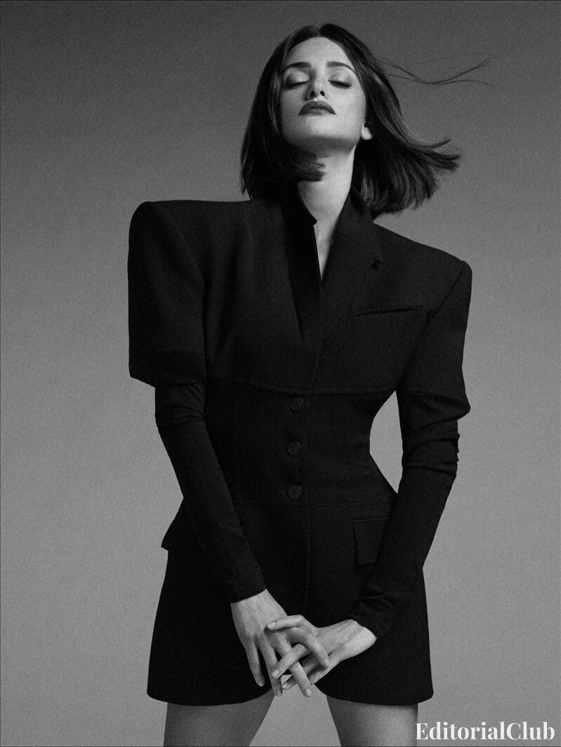 Penélope Cruz in black sculpted shoulder blazer, eyes closed, striking a powerful pose in monochrome editorial
