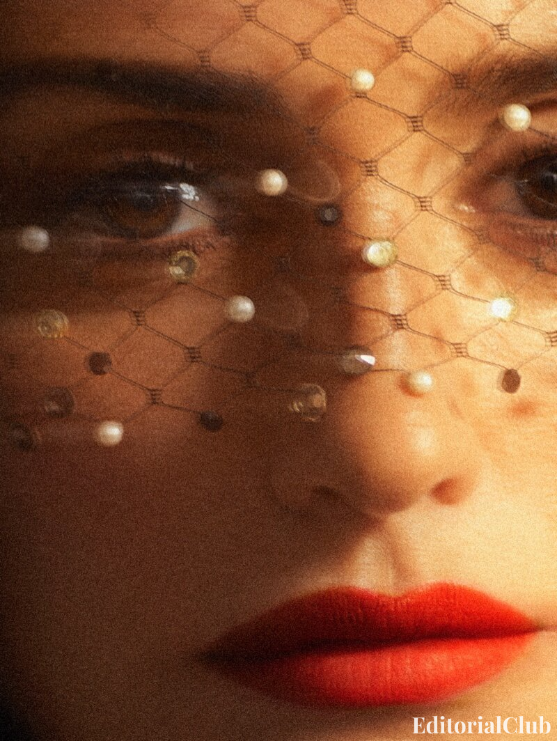 Close-up of Penélope Cruz's face behind pearl mesh veil with red lipstick, beauty shot for InStyle May 2021