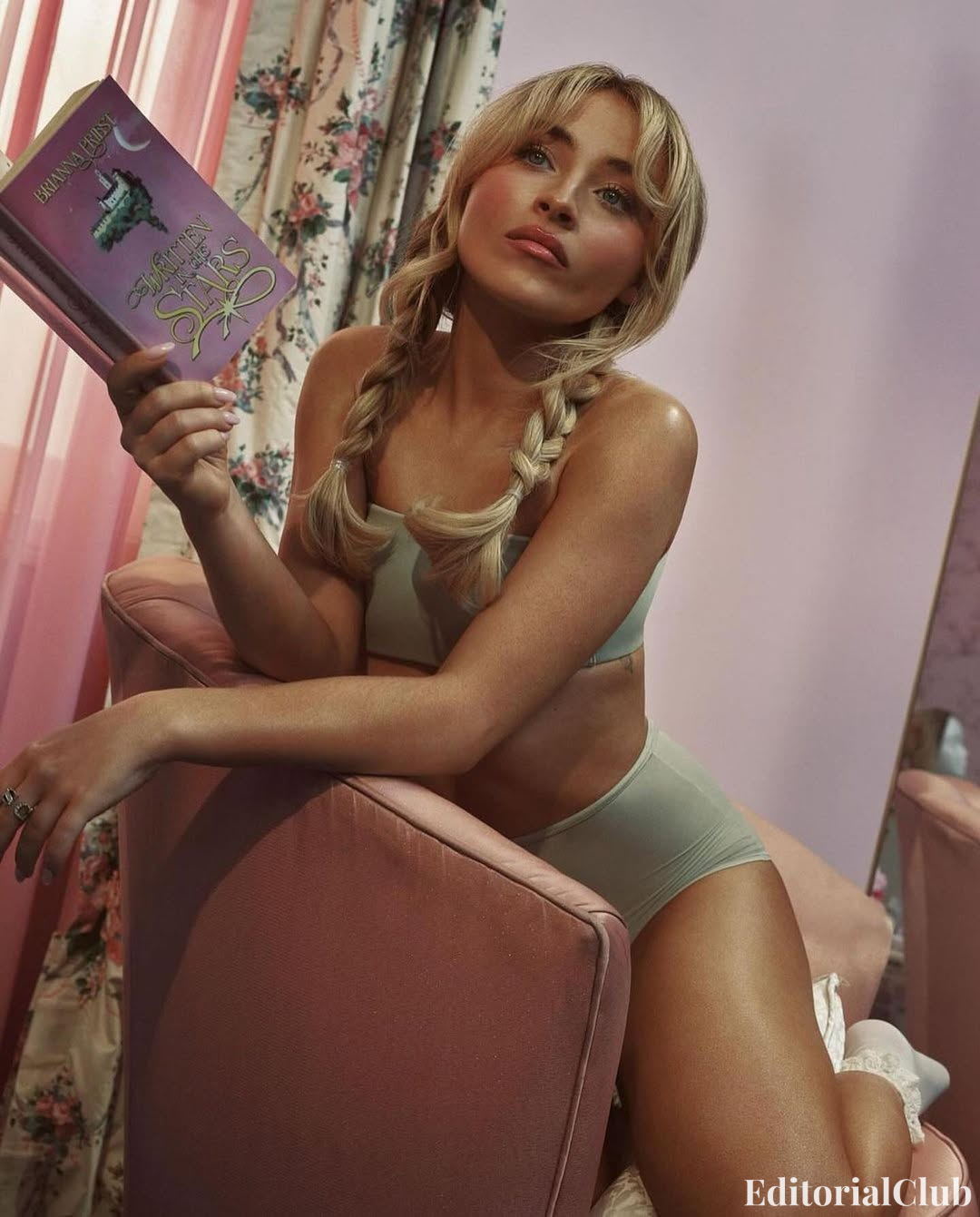 Sabrina Carpenter reading a pink book in blonde braids and minimal olive-toned lingerie, pastel room with floral curtains.